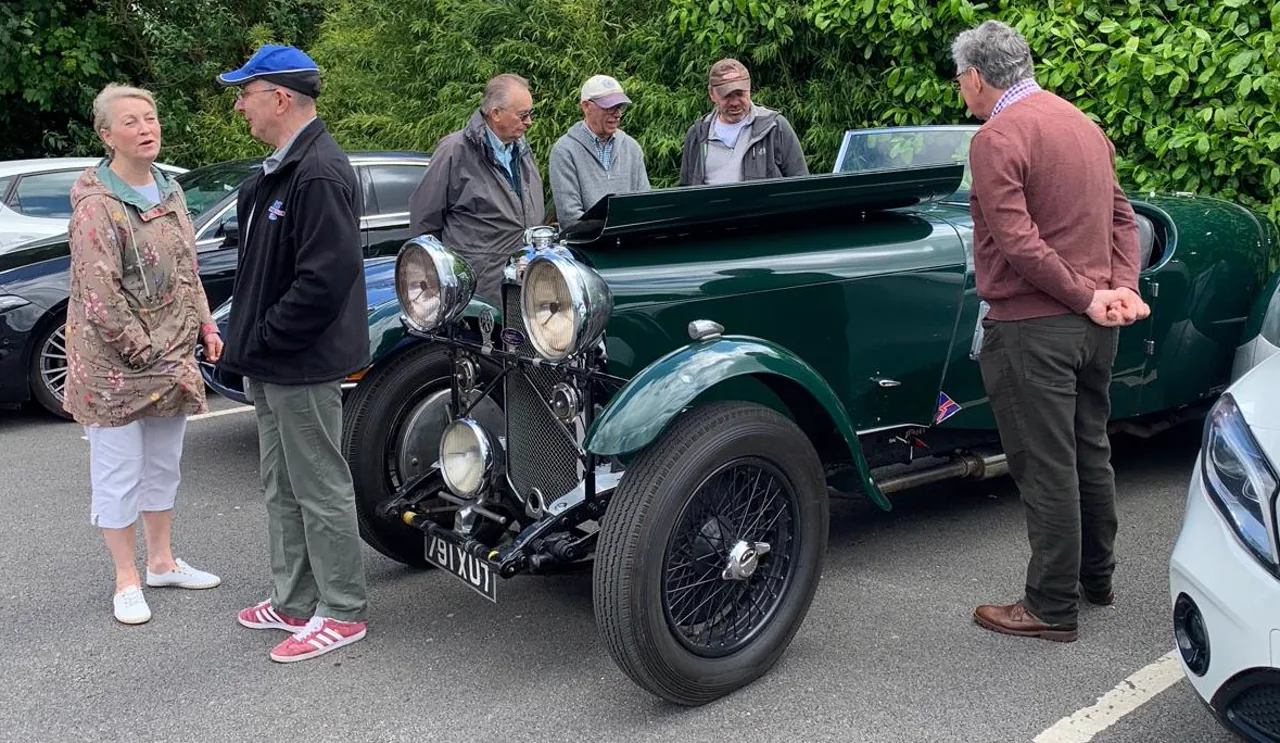 People gathered around a dark-green vintage tourer
