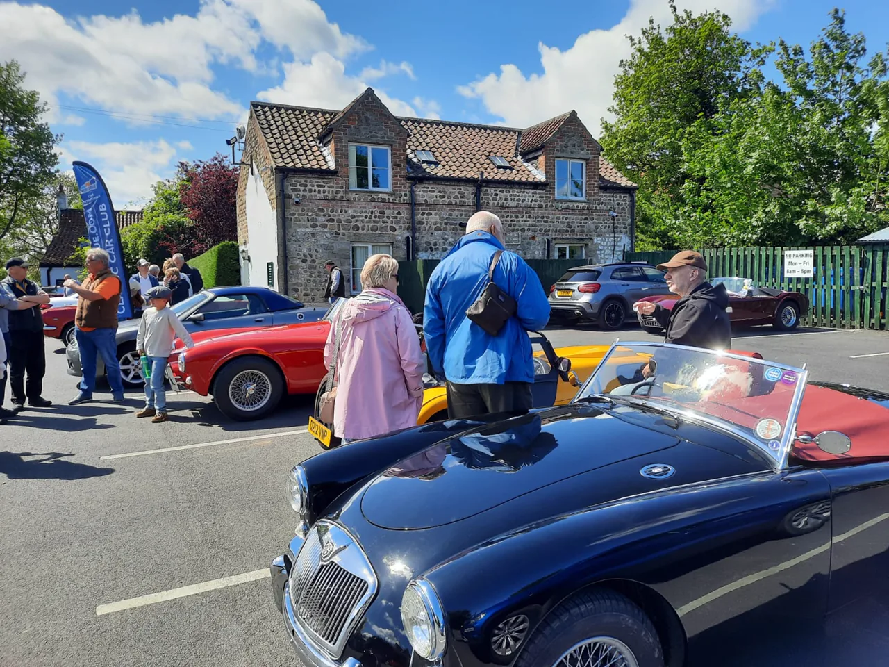 People meeting beside a blue classic MG at The Punch Bowl